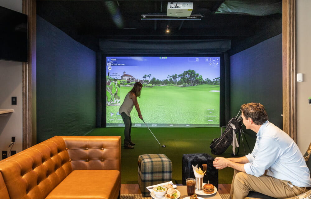 A couple utilizing a golf simulator
